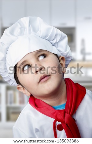 Funny boy dressed in chef, cooking in a kitchen