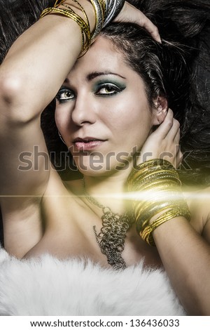 brunette young woman lying with golden jewelry, gold