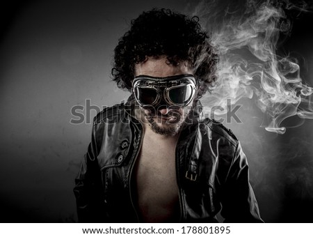 Hot, biker with sunglasses era dressed Leather jacket, huge smoke over dark background