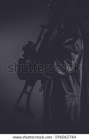 portrait of stylish man with long leather jacket, gun armed