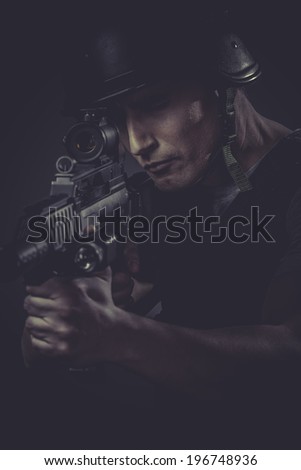 paintballing player wearing protective helmet aiming pistol ,black armor and machine gun