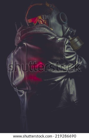 Man with gas mask and gun, dressed in black leather jacket