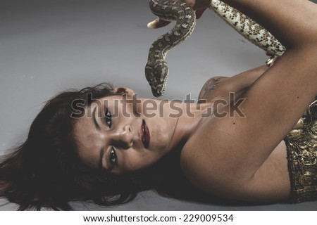 Sensual tattooed woman with big snake and iron corset