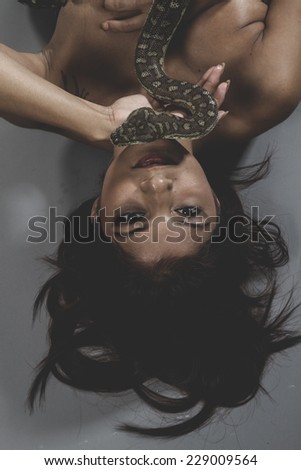 Sensual warrior tattooed woman with big snake and iron corset