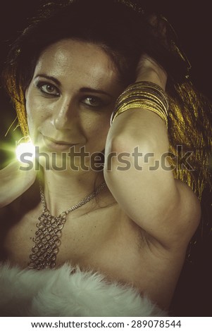 brunette woman wearing white fur and gold jewelry