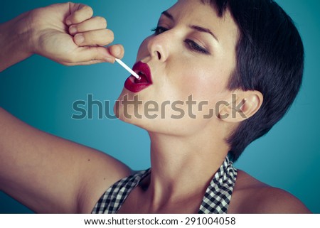 Eat, happy young woman with lollypop  in her mouth on blue background