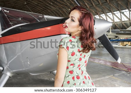 Airplane, pinup dressed in era of the Second World War, beauty redheaded woman
