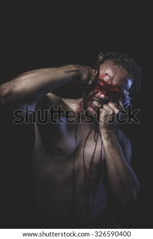 Rage, naked man with blindfold soaked in blood