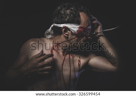 naked man with blindfold soaked in blood