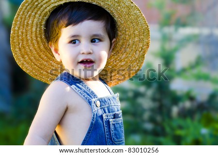 little baby gardener whith a hat teasingly smiling and enjoying his job