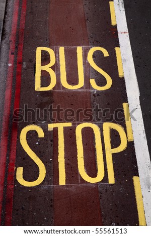 Yellow painted bus stop sign on a street. London