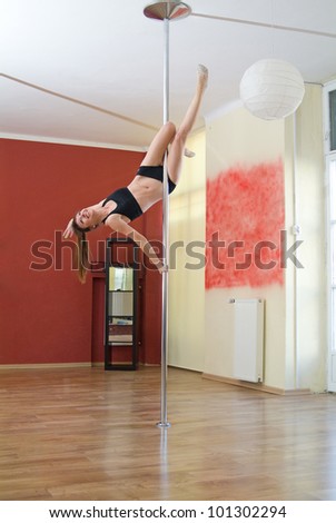 Beautiful girl performing pole dance at gym