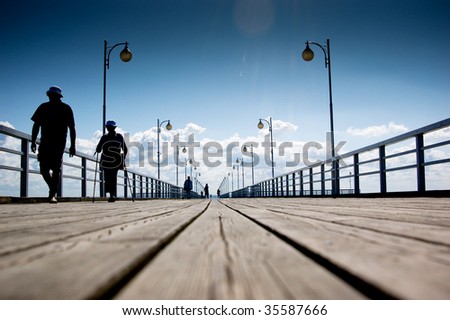 People waking along the wooden pier at the sea side.