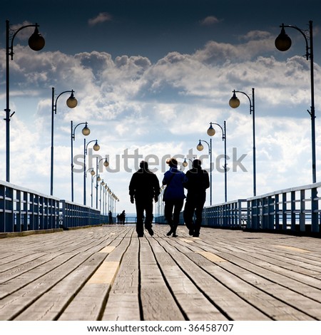 People walking along the wooden pier at the sea side.