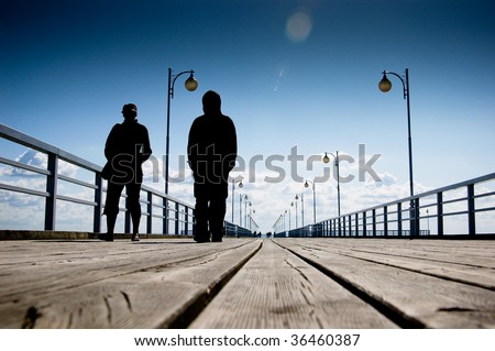 People walking along wooden pier at the sea side