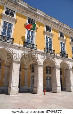 yellow building with portuguese flag surrounding Commerce Square in Lisbon, Portugal