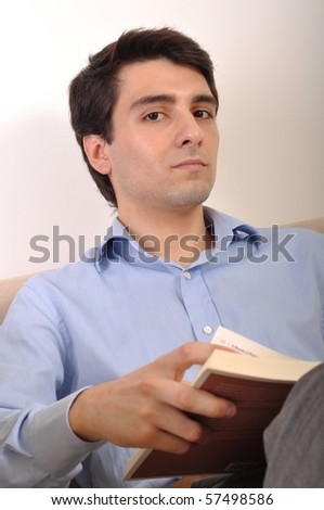 attractive young man reading a business book on the couch