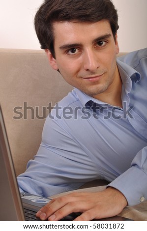attractive young man with laptop computer lying on the couch at home