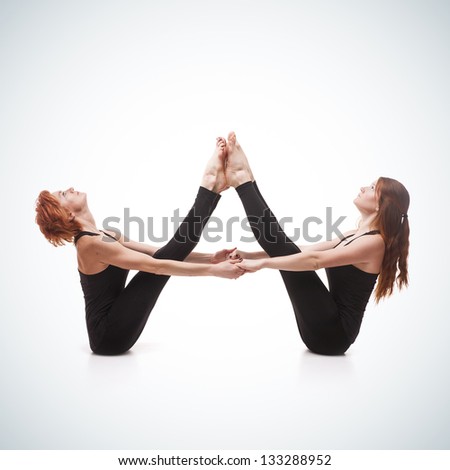 paired yoga. Two women practicing yoga on blue gradient background