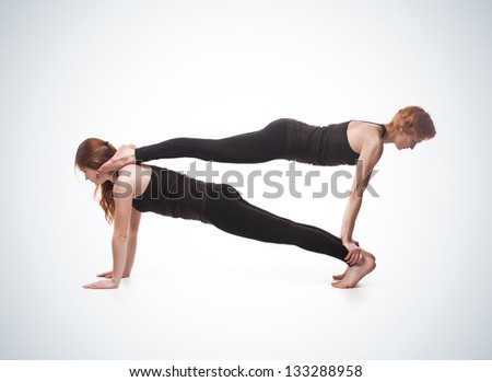 paired yoga. Two women practicing yoga on blue gradient background