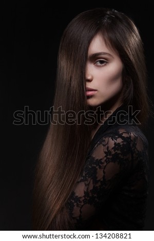 Pretty woman with long straight brown hair looking at camera, isolated on black background