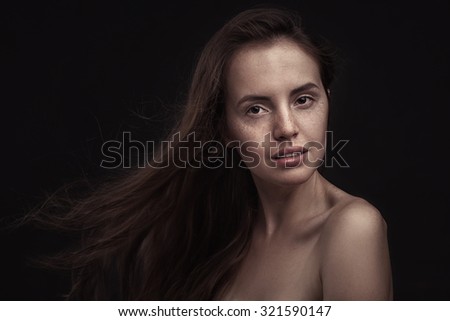 Beautiful woman  with long hair and freckles on dark studio background