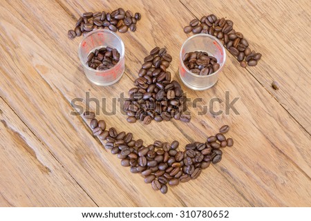Coffee beans in smile face shape on wood table