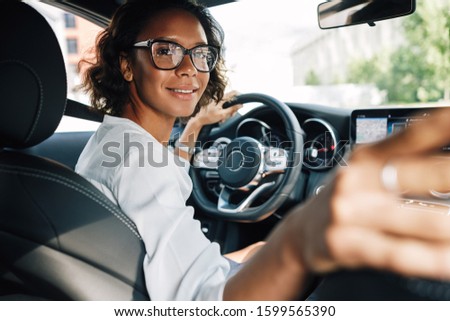 Similar – Image, Stock Photo Young smiling woman steering car at sunset