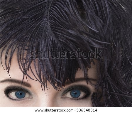 Close-up portrait of mysterious beautiful woman with deep blue eyes in black feather headdress. Model fashion shooting. Smoky eyes make-up. Perfect pure skin. Femme fatale. Retro style. Vintage style.