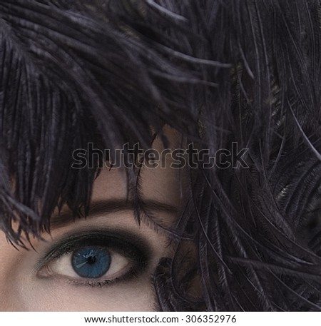 Close-up portrait of mysterious woman with deep blue eyes in black feather headdress. Model fashion shooting. Smoky eyes make-up. Perfect pure skin. Femme fatale. Retro style. Vintage style.