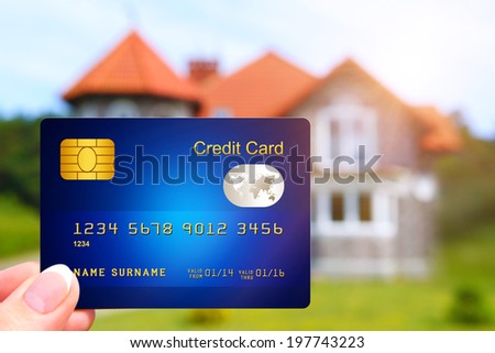 hand holding credit card with house as a background. focus on card.