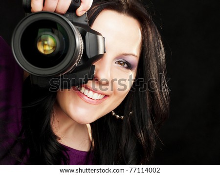 smiling brunette photographer woman holding camera over dark background