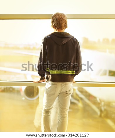 Young man looking out the window at airport