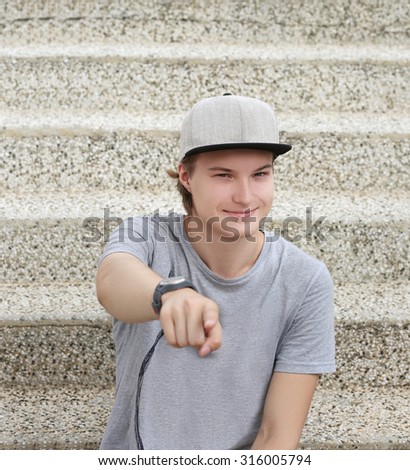Portrait of smiling teenage boy pointing at the camera.