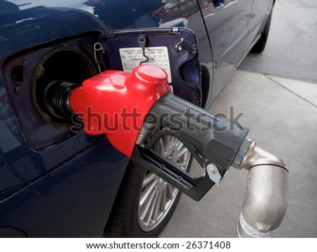 filling up a car with gasoline showing a gas nozzle inserted into a car\'s gas tank  hole