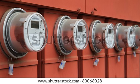 Line up of five electric power meters on red electrical panels