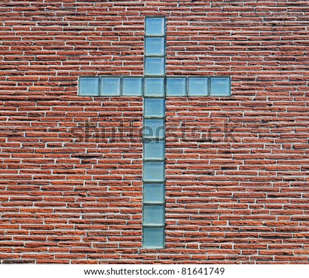 Blue glass brick or block cross on a thin red brick wall of a church