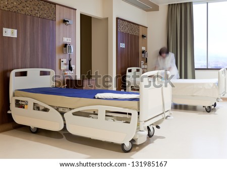 Blurred image of staff member in medical uniform fixing hospital bed