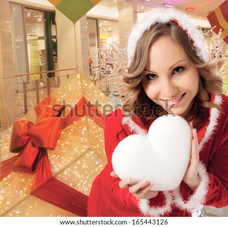 happy smiling Santa woman indoors, holding white heart, background digitally added, work path