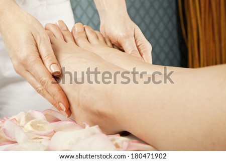 woman foot receiving gentle massage on bed with rose petals in spa