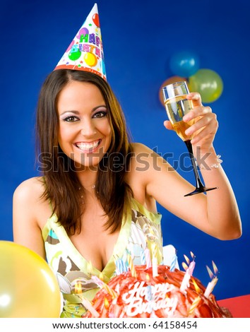 Happy female celebrating with glass of champagne and party hat over birthday cake