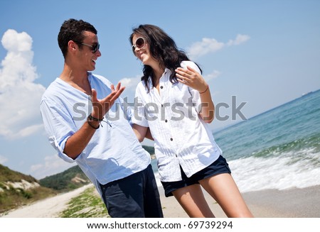 Young happy couple hugging and talking along a solitary beach