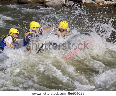 Group of four men whitewater rafting in river