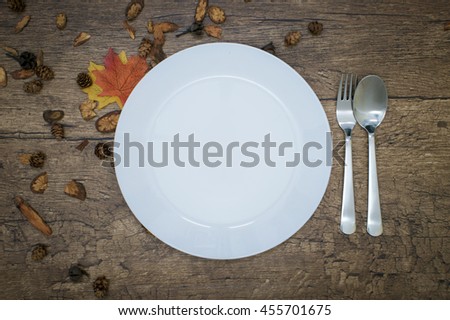 Empty white plate with spoon and folk over wooden background.