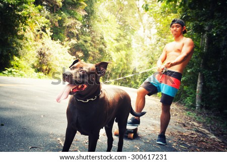 Young man with black dog running on a rural road during sunset at streets dry leaf