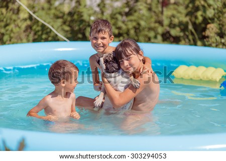 children swim in the pool with the dog
