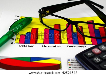 Colorful sales charts, calculator, blue pen and glasses