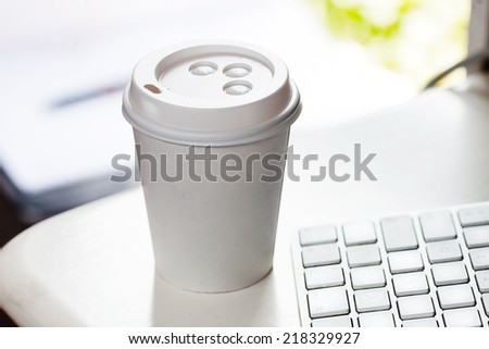 Disposable coffee cup on table near computer keyboard