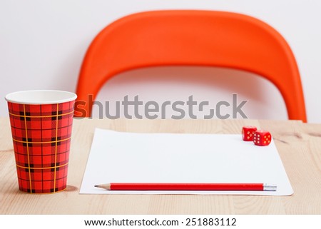 Work place with paper, dice, red pencil and disposable cup of coffee.