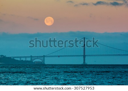 The full moon setting behind the Golden Gate Bridge and the fog just before sunrise.